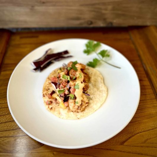 Prepared shrimp tacos with sauce, pico de gallo, red cabbage and cilantro