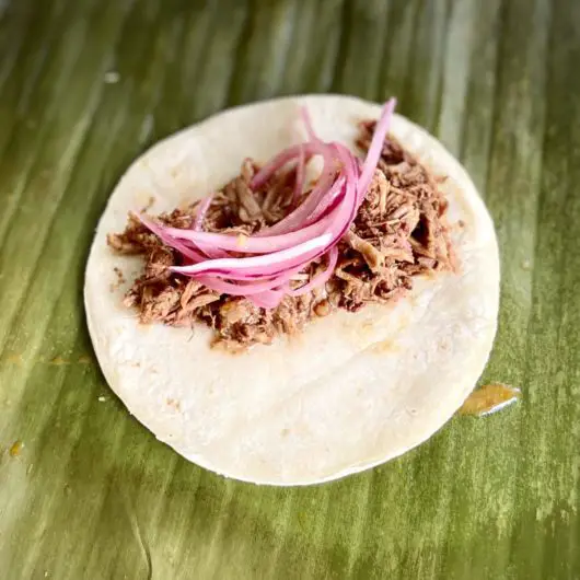 Cochinita pibil tacos served with pickled onions