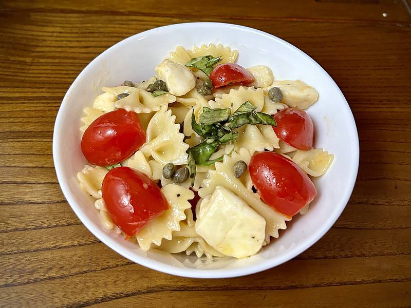 Tricolor Caprese Cold Pasta salad with the vibrant colors of the Italian flag, Green basil and capers, white mozzarella, and red grape tomatoes.