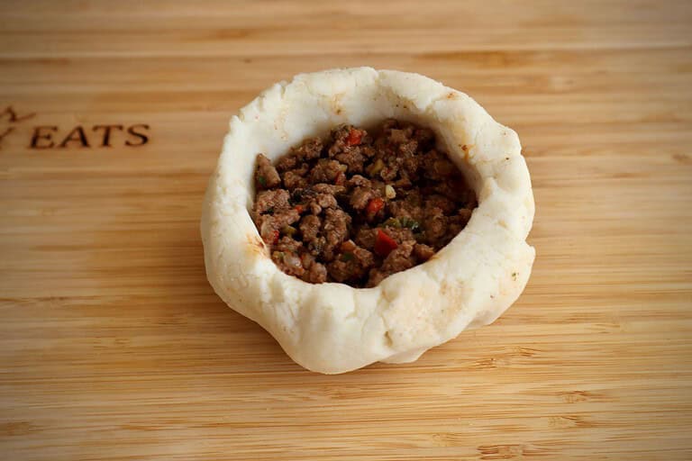 Filling the bollo pelon with filling before closing and cooking.